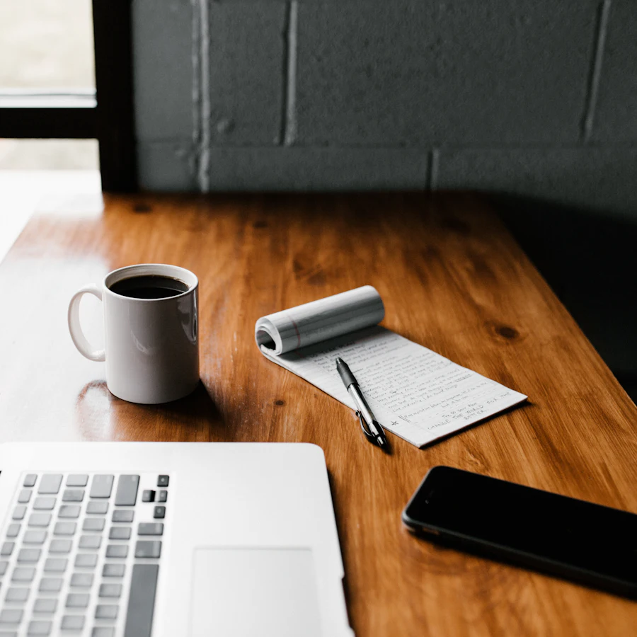 Laptop, coffee mug and phone on a work desk