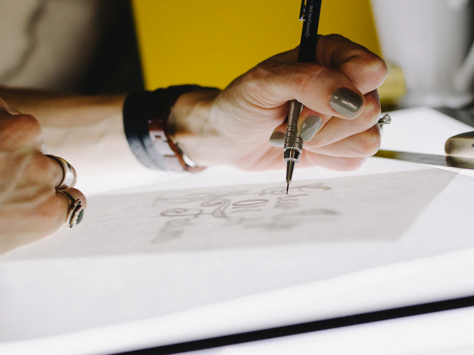 Hand-lettering a logo sketch with a pencil