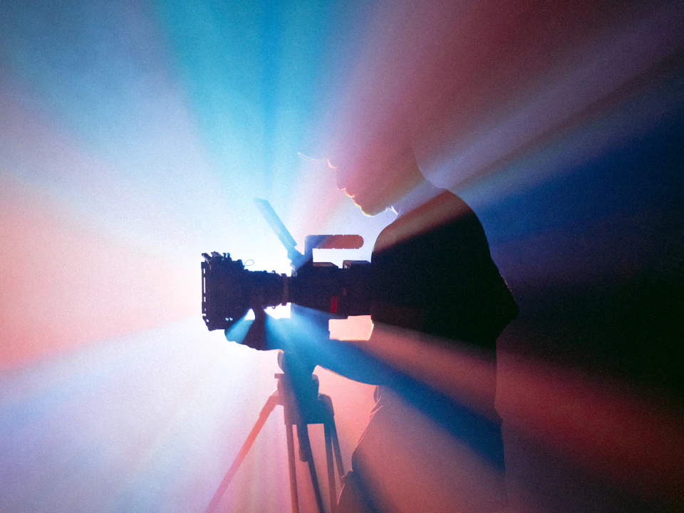 Video camera on a tripod filming in coloured studio lights